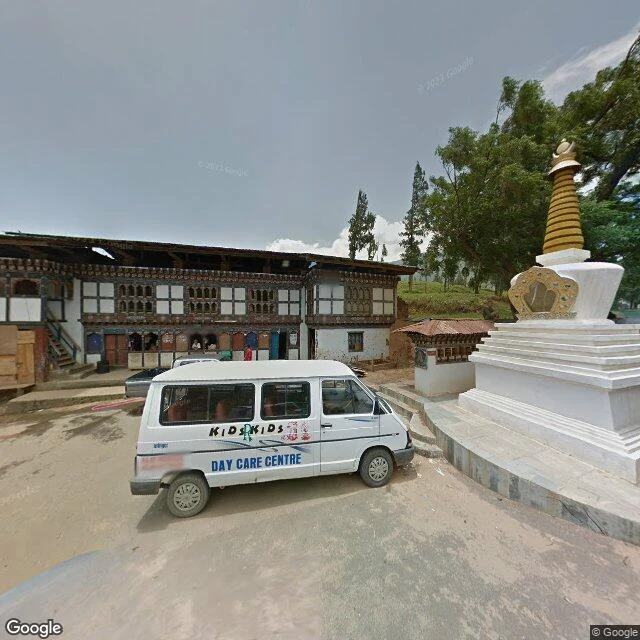 Street-level view of Wangdue Phodrang Dzong: a white chorten with a gilded spire beside a fire-damaged building.