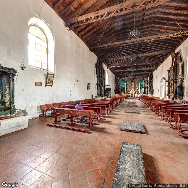 one man seated in a church nave, back to the camera