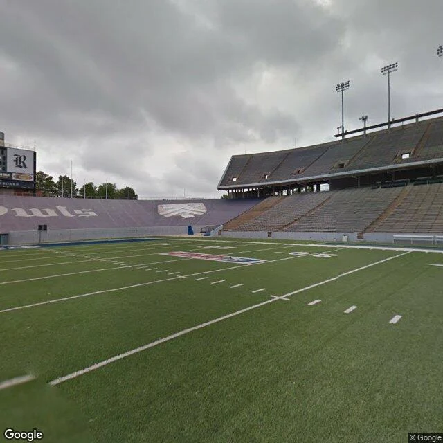 The empty field at Rice Stadium, purple "Owls" end zones, vacant stands, overcast sky