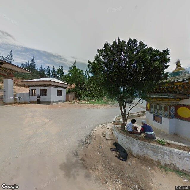 The gate at the approach to Wangdue Phodrang Dzong: guard post, white pillars and a barrier arm.